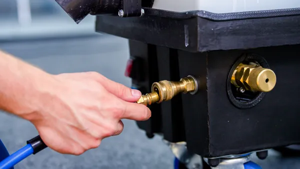 Technician connecting the solution hose to professional cleaning equipment before an on-site curtain clean